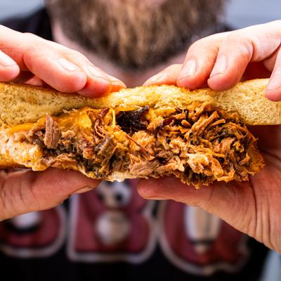 Hands holding the brisket grilled cheese.