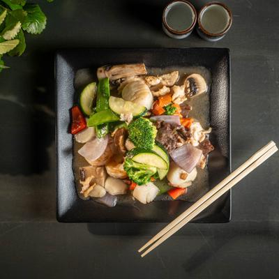 Mixed vegetables and meat stir fry with chopsticks on the plate.