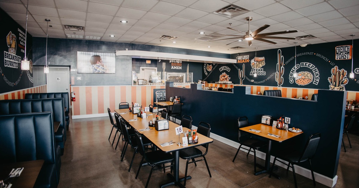 Modern diner-style interior space with booth benches and tables with chairs arranged in the center
