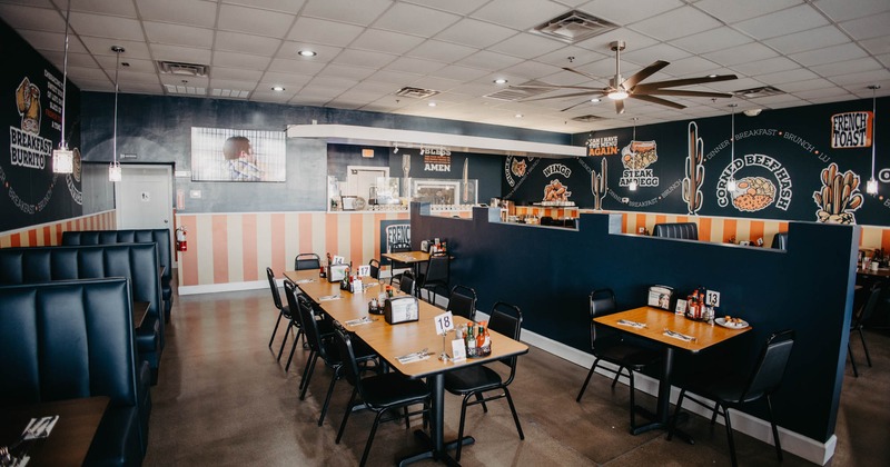 Modern diner-style interior space with booth benches and tables with chairs arranged in the center