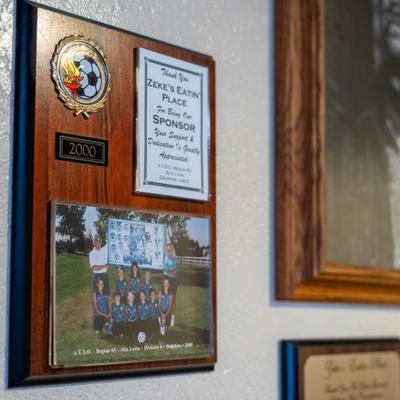 Wooden wall plaque with a team picture, a certificate, and a small emblem.