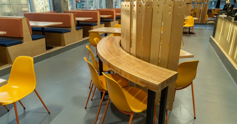 Interior of a café with booths and yellow chairs at a curved communal table
