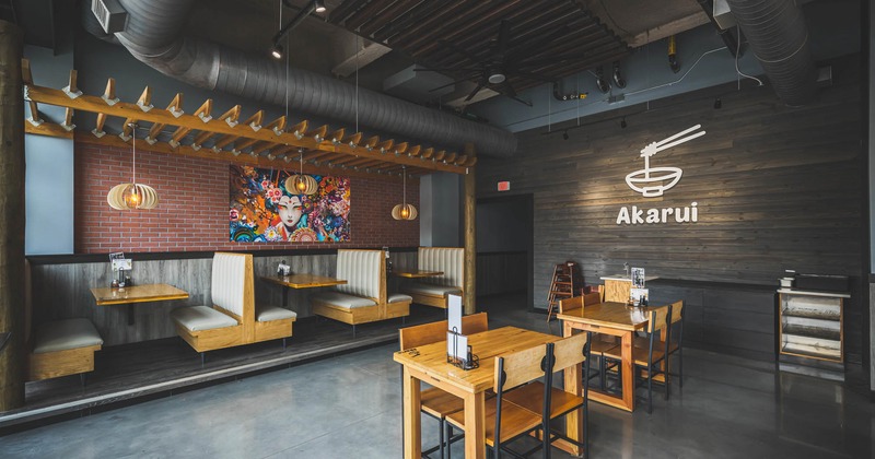 Inside, booths by a wall with colorful painting and pendant lights, two individual tables