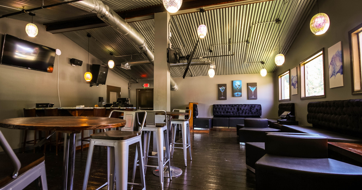 Indoor seating area with high round tables and chairs on the left and booths on the right