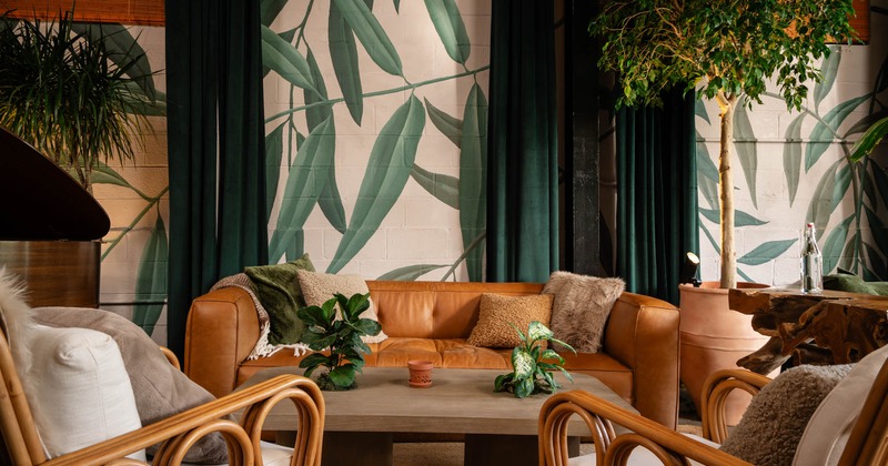 Interior, lounge area, three seater sofa with armchairs and low table, plant mural on the wall