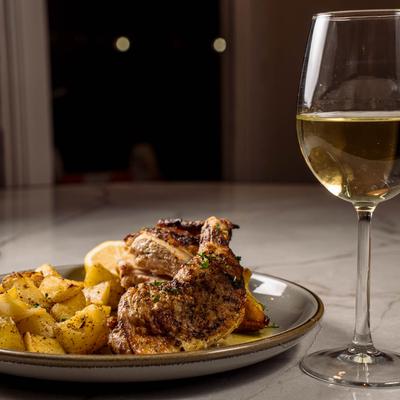Roasted half chicken, potatoes, and a glass of white wine.