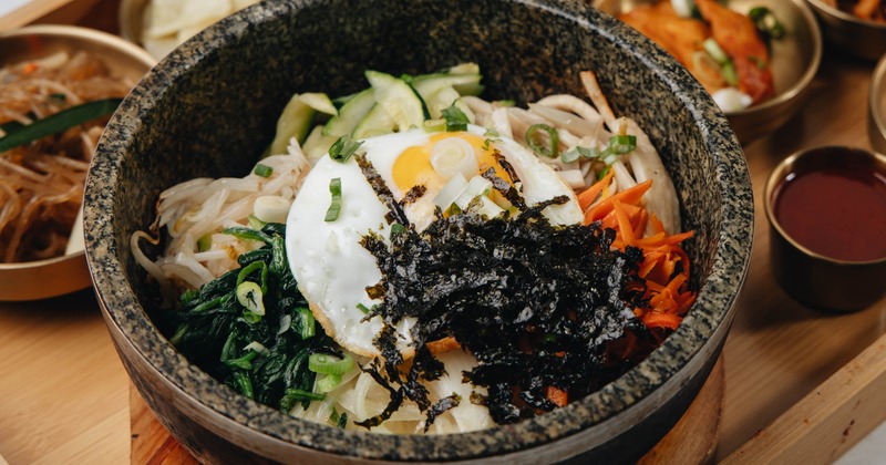 Bibimbap topped with seasoned vegetables, meat, a fried egg, and seaweed