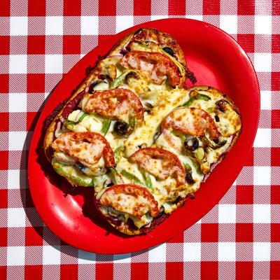 Toasted sub topped with cheese on a red plate.