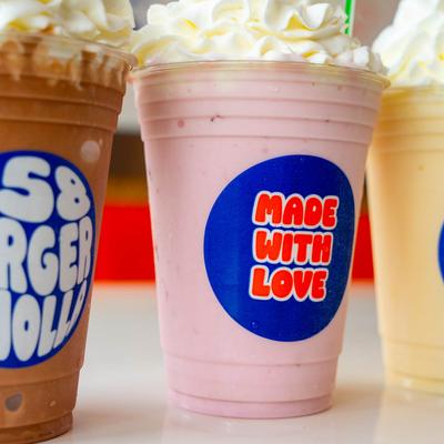 Strawberry milkshake with whipped cream alongside chocolate and vanilla shakes.
