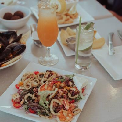 Calamari over a salad, served on the table with various other dishes and drinks.