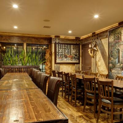 Dining room with long wooden tables, wall art, and plants.