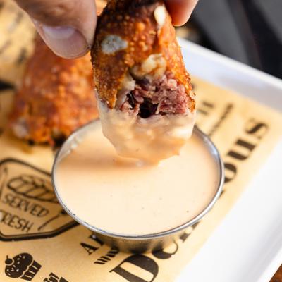 Corned beef roll dipped in sauce.