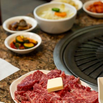Korean BBQ set featuring raw beef ready for grilling, served with banchan sides.