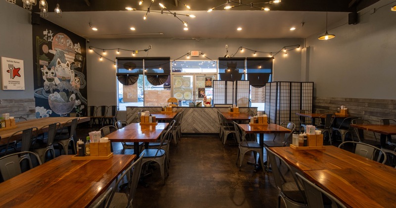 Interior of a ramen restaurant with wooden tables, metal chairs
