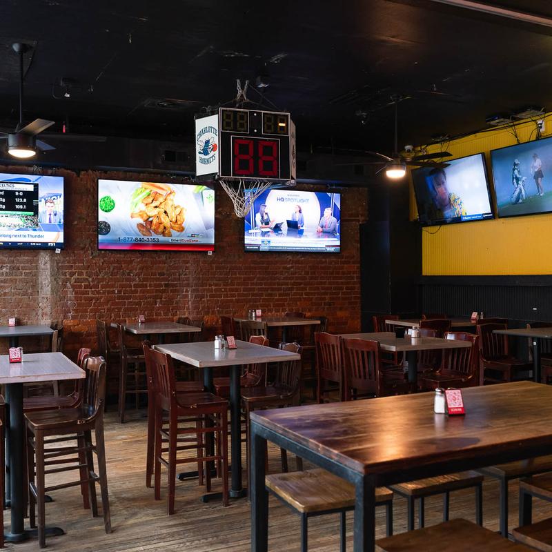 Interior, wooden tables and stools with TVs on the walls