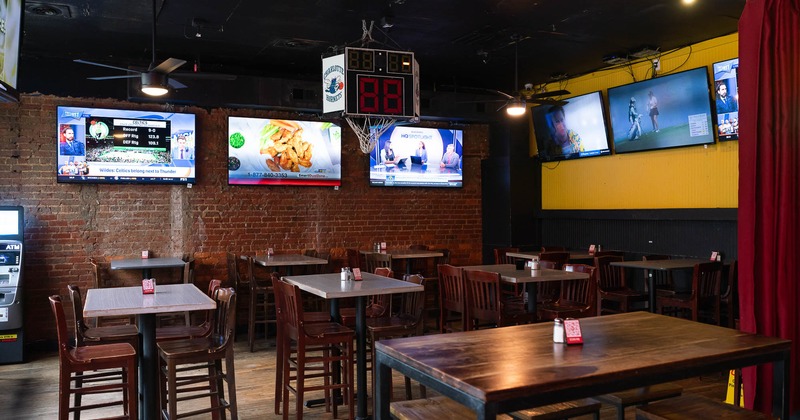 Interior, wooden tables and stools with TVs on the walls