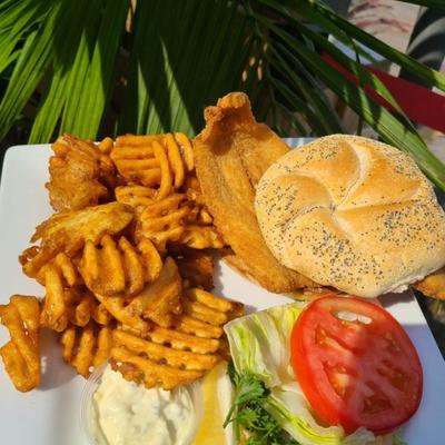 Flounder on a Roll, served with lettuce, tomato, and fries.