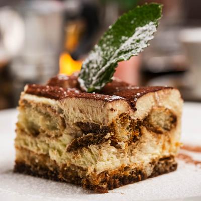 A close-up of a slice of tiramisu topped with a mint leaf.