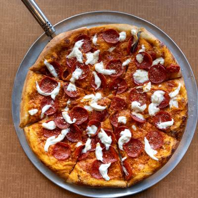 Pizza topped with vodka sauce, pepperoni, and burrata.