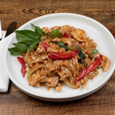 Thai stir-fry noodles with red chili peppers and basil leaves.