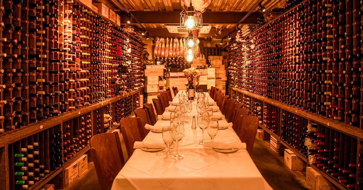 Interior, long dining table waiting for guests, wine racks