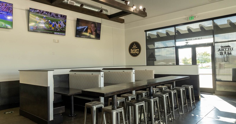 Interior, booths and a table with bar stools, TVs on a wall