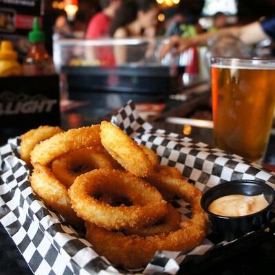 Onion rings with dip on the side. glass of beer in the back