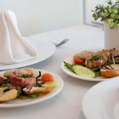 Salad plates with sliced meat and vegetables served on a white table.