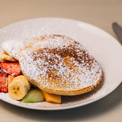 Pancakes dusted with powdered sugar, served alongside a medley of fresh fruit.