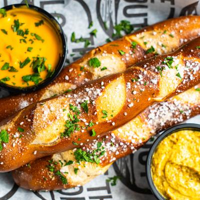 Pretzel Sticks accompanied by beer cheese sauce and mustarg, close-up.