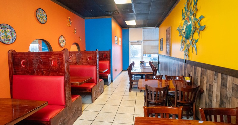 Interior of a colorful restaurant with red vinyl booths, wooden tables, and vivid orange