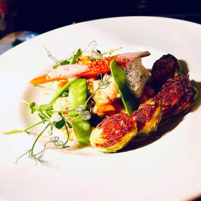 Crispy Brussels sprouts and snap peas arranged elegantly on a white plate with microgreen garnish.