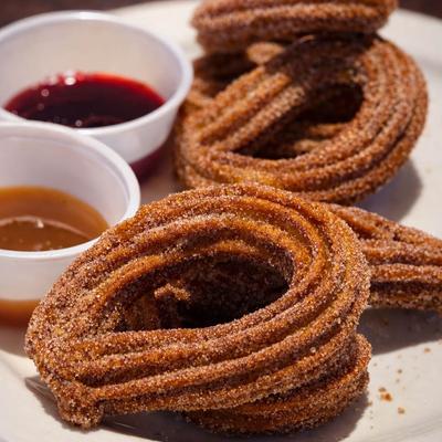 Churros topped with cinnamon sugar, served with strawberry and caramel sauce.