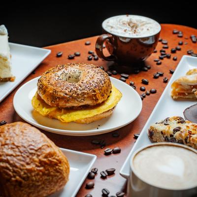 Breakfast bagel served alongside other pasties and a cup of coffee.