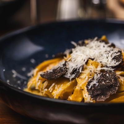 Pasta topped with shaved truffle and grated cheese.