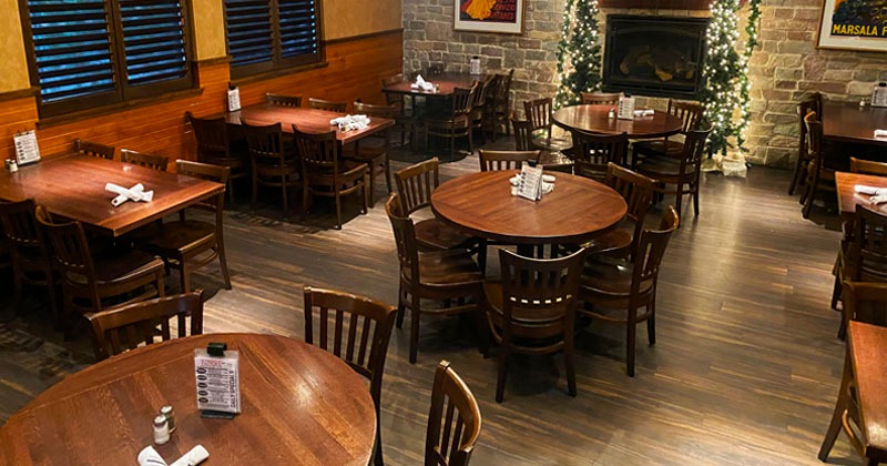 Dining area with a stone fireplace, wooden tables, and festive decorations