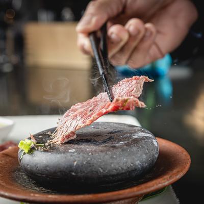 A hand grabbing food with chopsticks.