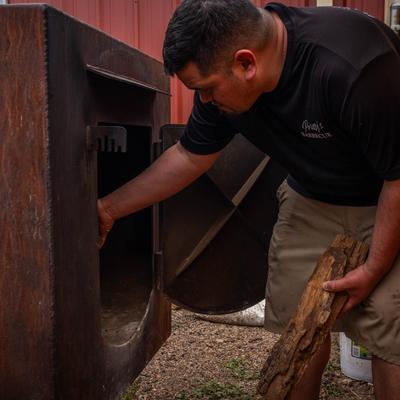 Owner filling the smoker with wood.