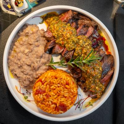 Marinated skirt steak with house chimichurri sauce, with beans and rice on the side.