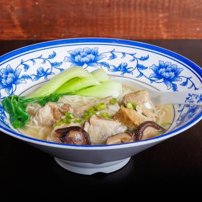 Rib and mushroom soup with bok choy and scallions in a blue floral bowl.