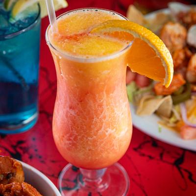 Twisted Daiquiri served in hurricane glass and garnished with an orange slice.