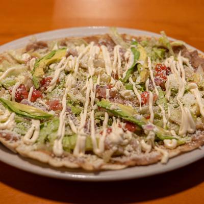 Corn dough flatbread topped with various ingredients.