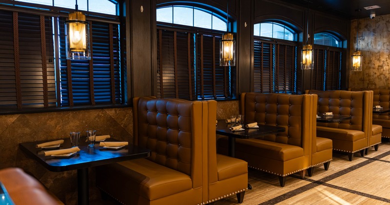 Interior with brown leather booths, arched windows, and warm pendant lighting