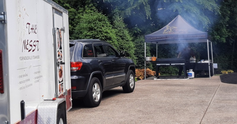 Outdoors, the Nesst catering trailer parked in front of a grill