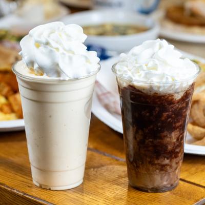 Two different milkshakes topped with whipped cream.
