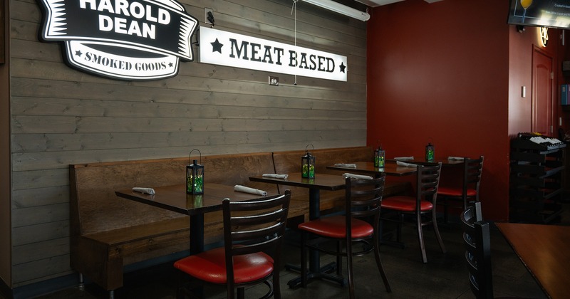 Dining tables for two lined up, restaurant's logo on the wall