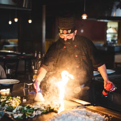 A person preparing food on an open flame