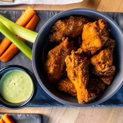 Fried chicken wings served with celery and carrot sticks and a dip.