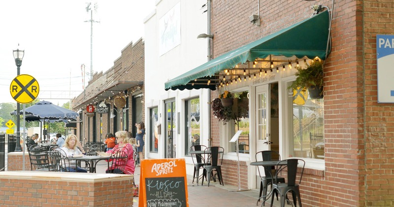 Partially covered sidewalk cafe with tables, chairs, and guests