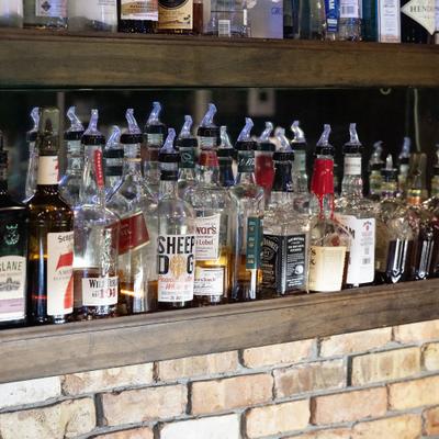 Bar shelves filled with liquor bottles above the brick wall.